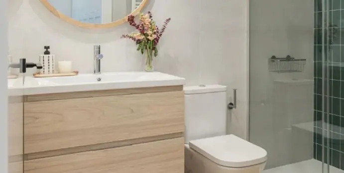 A bathroom with a sink, toilet and mirror.