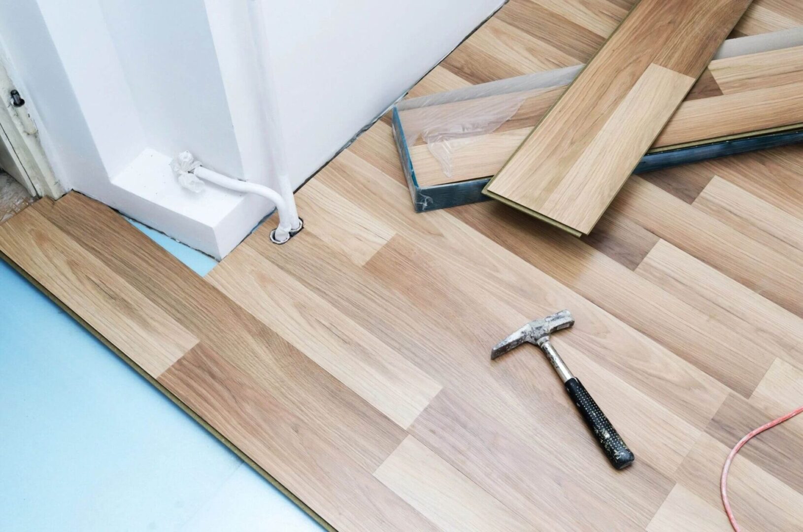 A hammer and some wood flooring laying on the floor