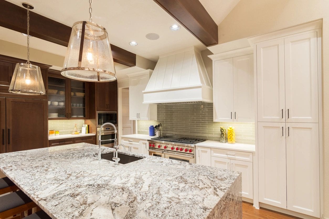 A kitchen with white cabinets and granite counter tops.